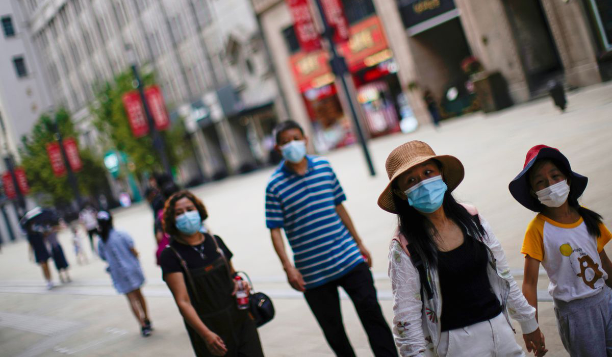 People wearing protective face masks walk on a street in China